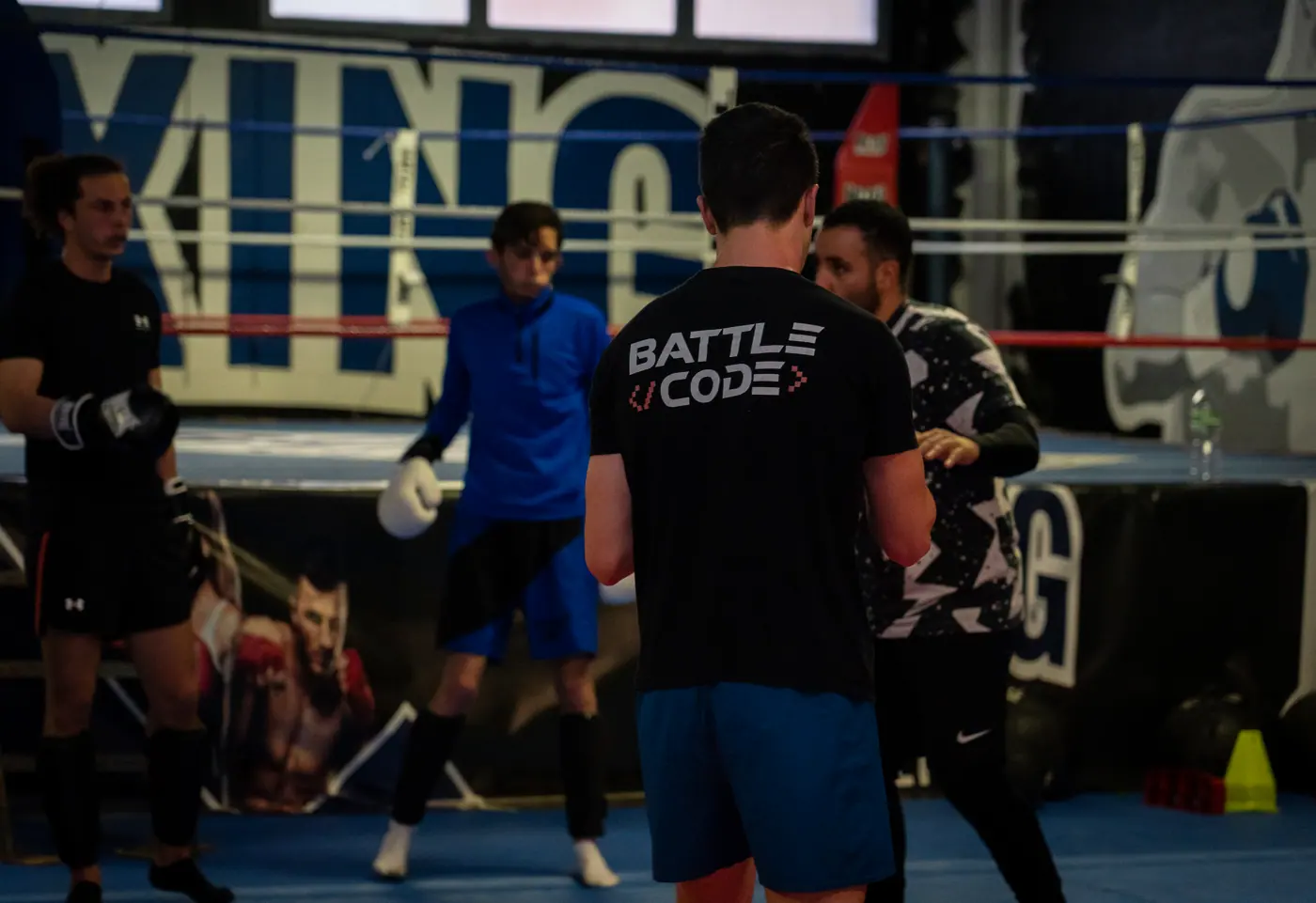 Un coach donne la consigne à un groupe monté sur le ring, gants aux mains